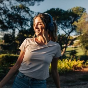 אישה מחייכת בזמן הליכה בפארק, אוזניות באוזניים ושמש רכה על הפנים