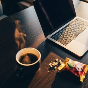 שולחן עבודה עם מחשב, כוס קפה וחטיף פתוח ליד המקלדת